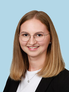 Junge weibliche Mitarbeiterin mit blonden Haaren und Brille.