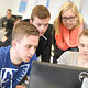 Vier junge Menschen sitzen vor einem Computer und bearbeiten etwas. 